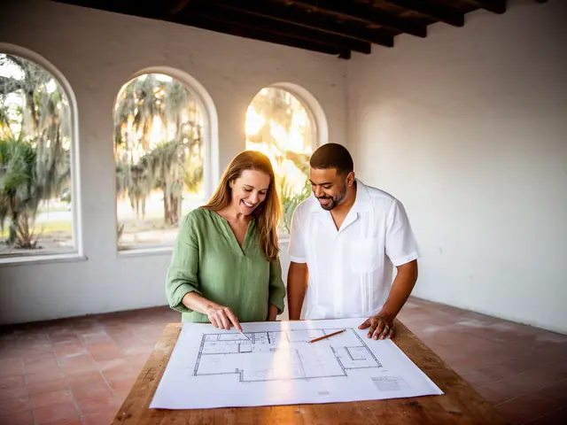Two business partners looking over a pencil floor sketch in an empty storefront.